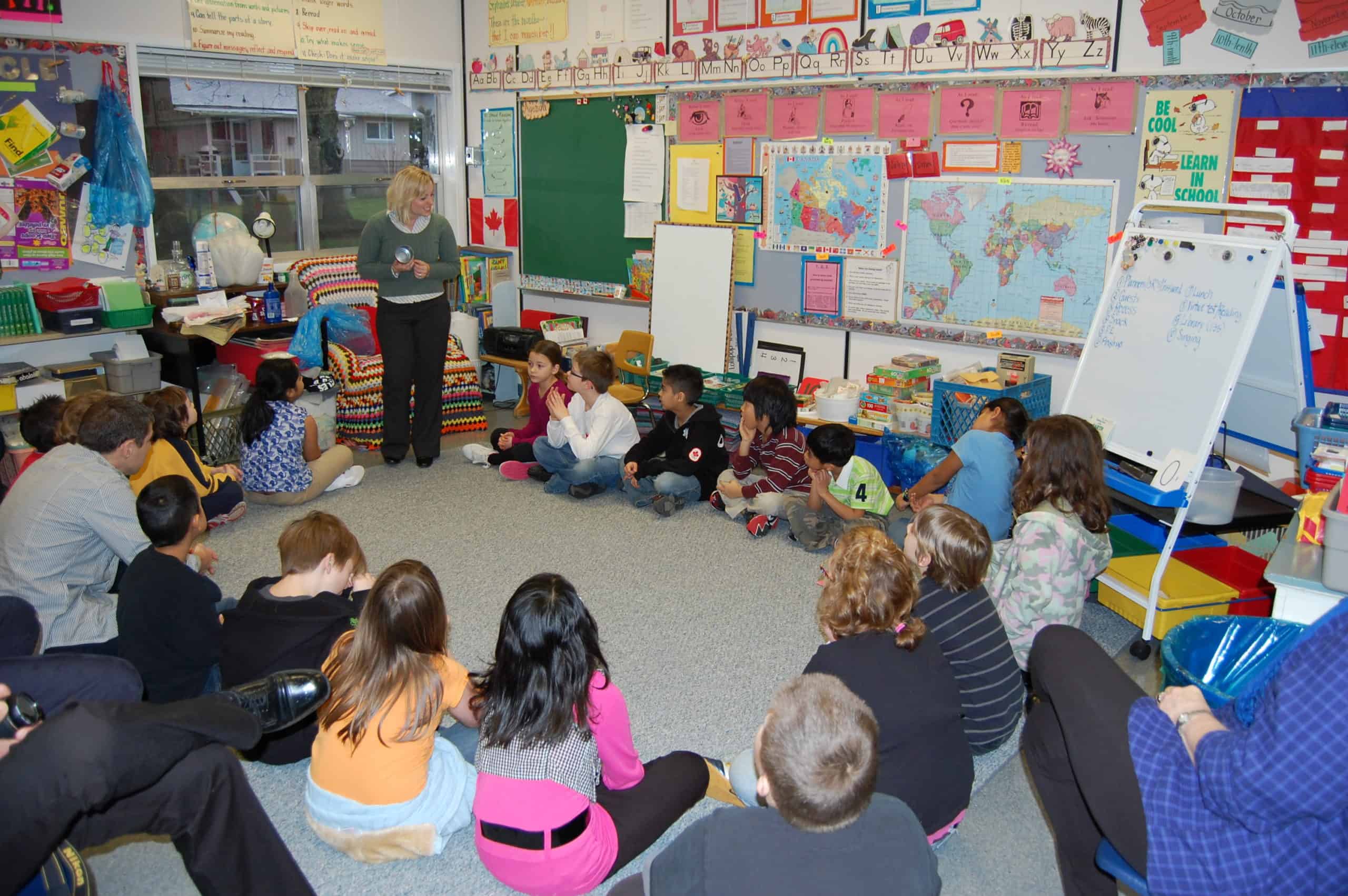 children sit in a circle and listen to a teacher