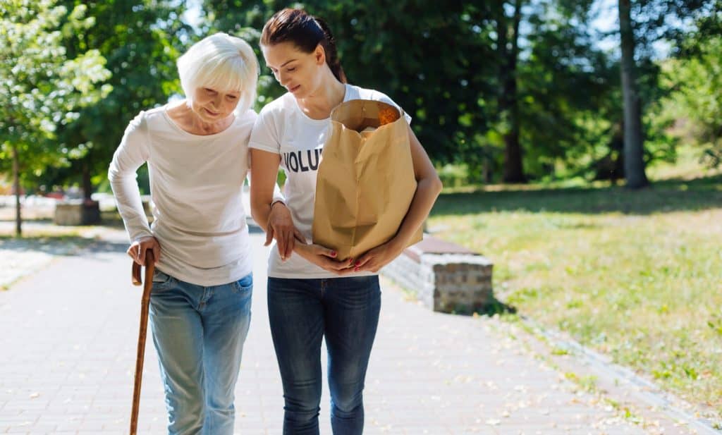 woman assisting elderly lady carry her groceries