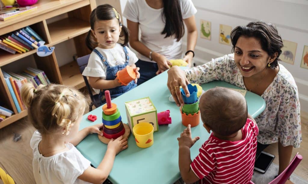 child care worker plays with young children at a day care