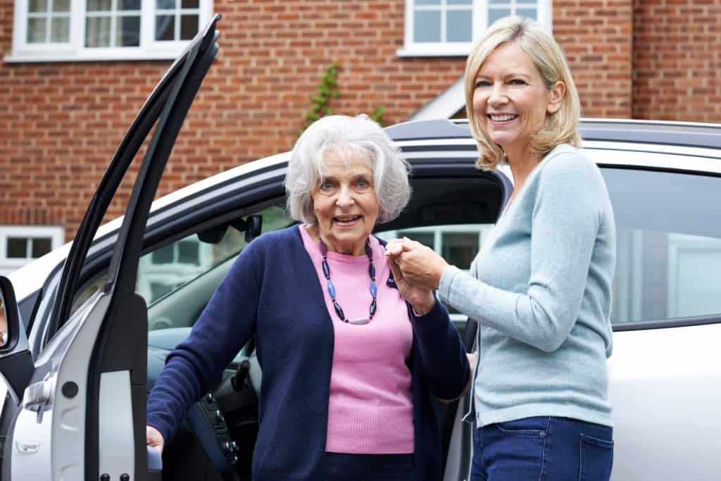 volunteer helping a senior get out of a vehicle to her medical appointment