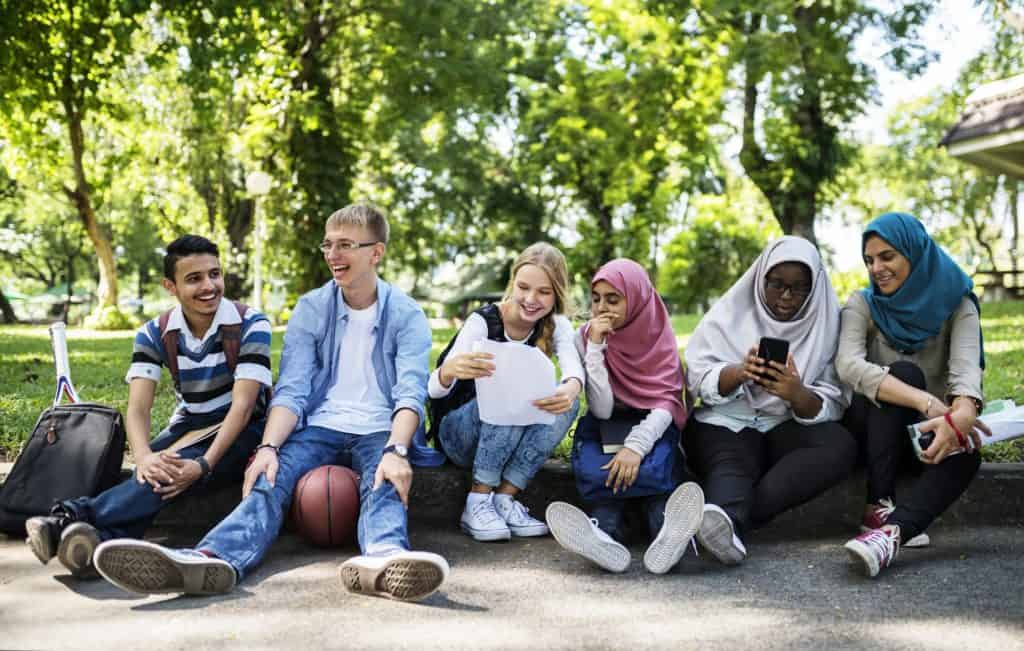 happy group of diverse youth sitting outside