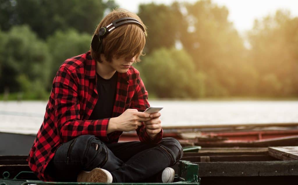 teenage boy listens to music outdoors on a dock