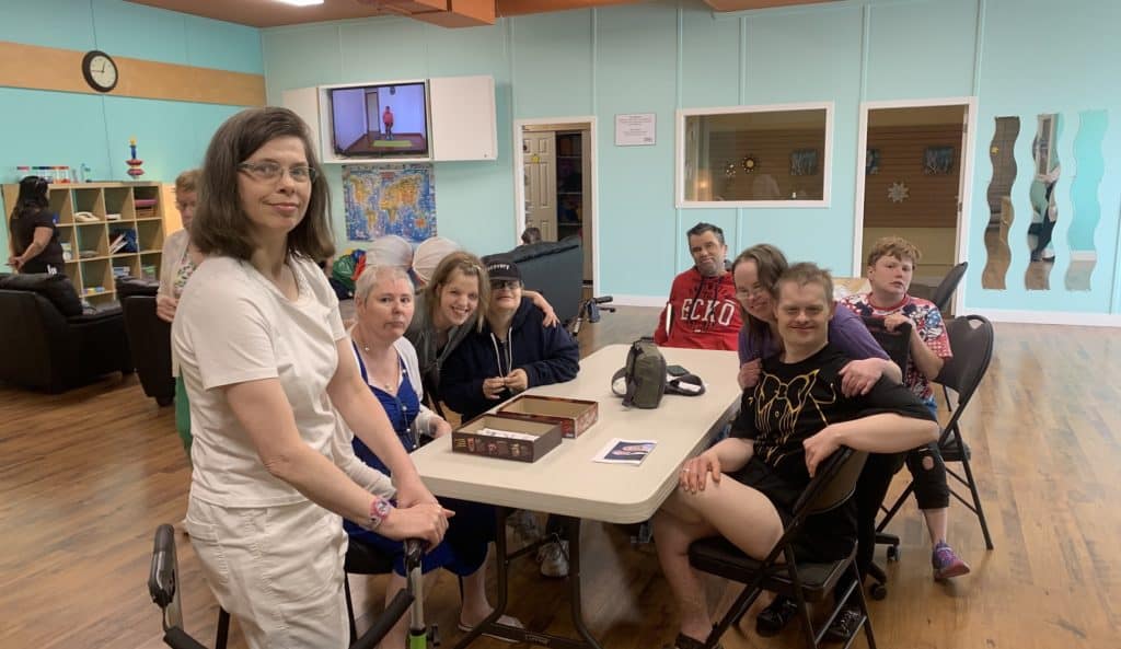 group of persons with disabilities sitting around a table in a community room