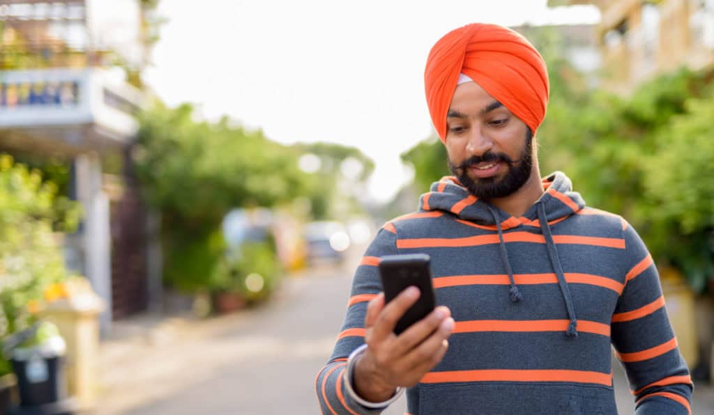 young indian Sikh man using his mobile phone