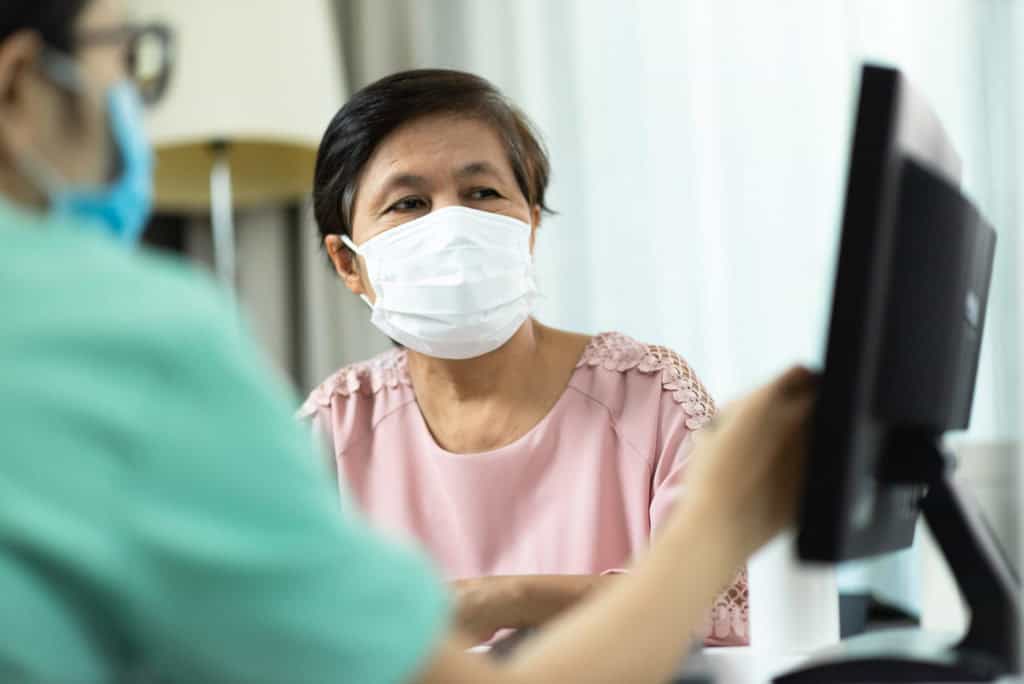 nurse helping an asian senior in doctor's office