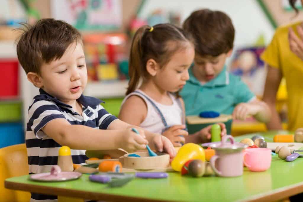 Three children playing with toys on a table