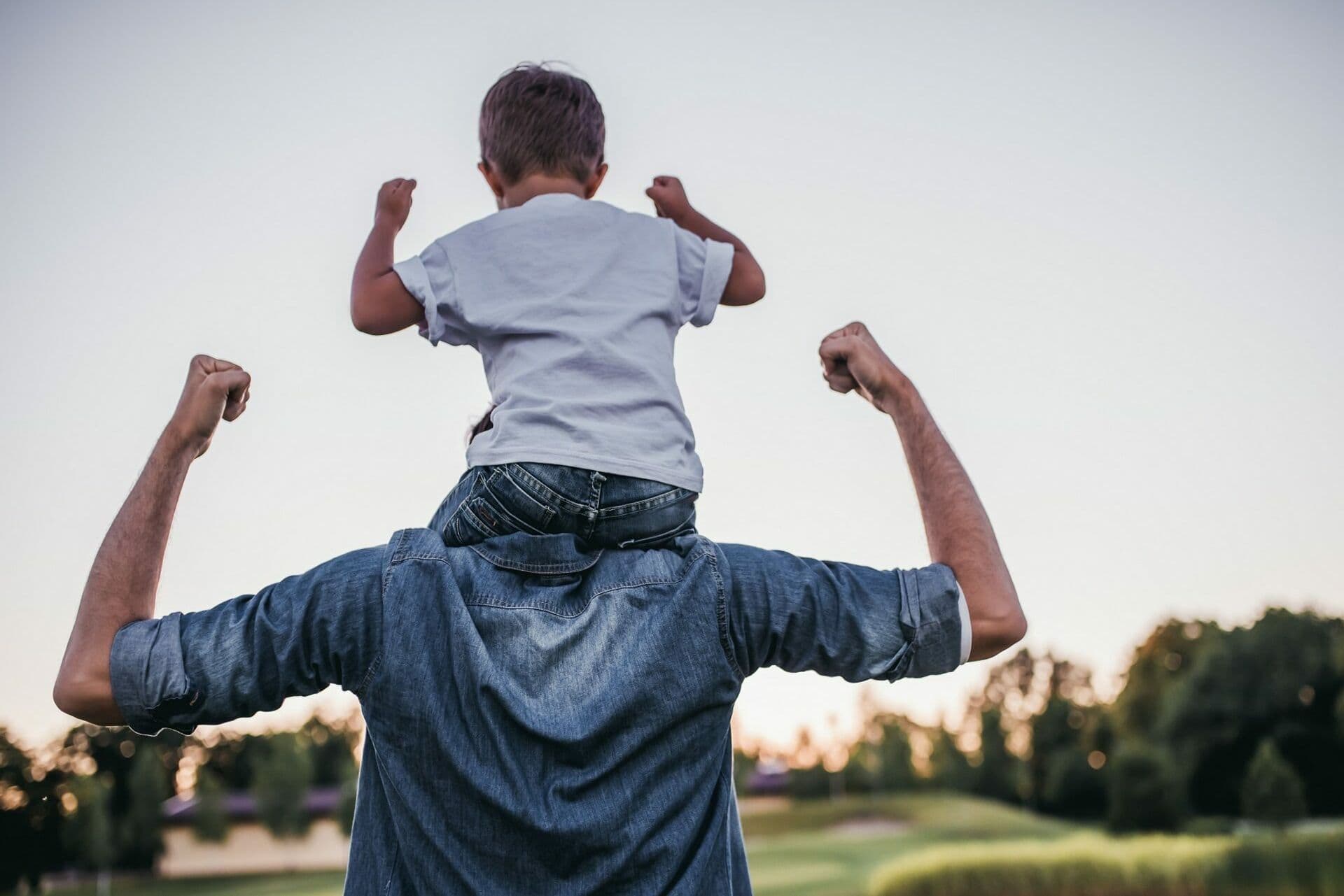young boy sits on his dad's shoulders