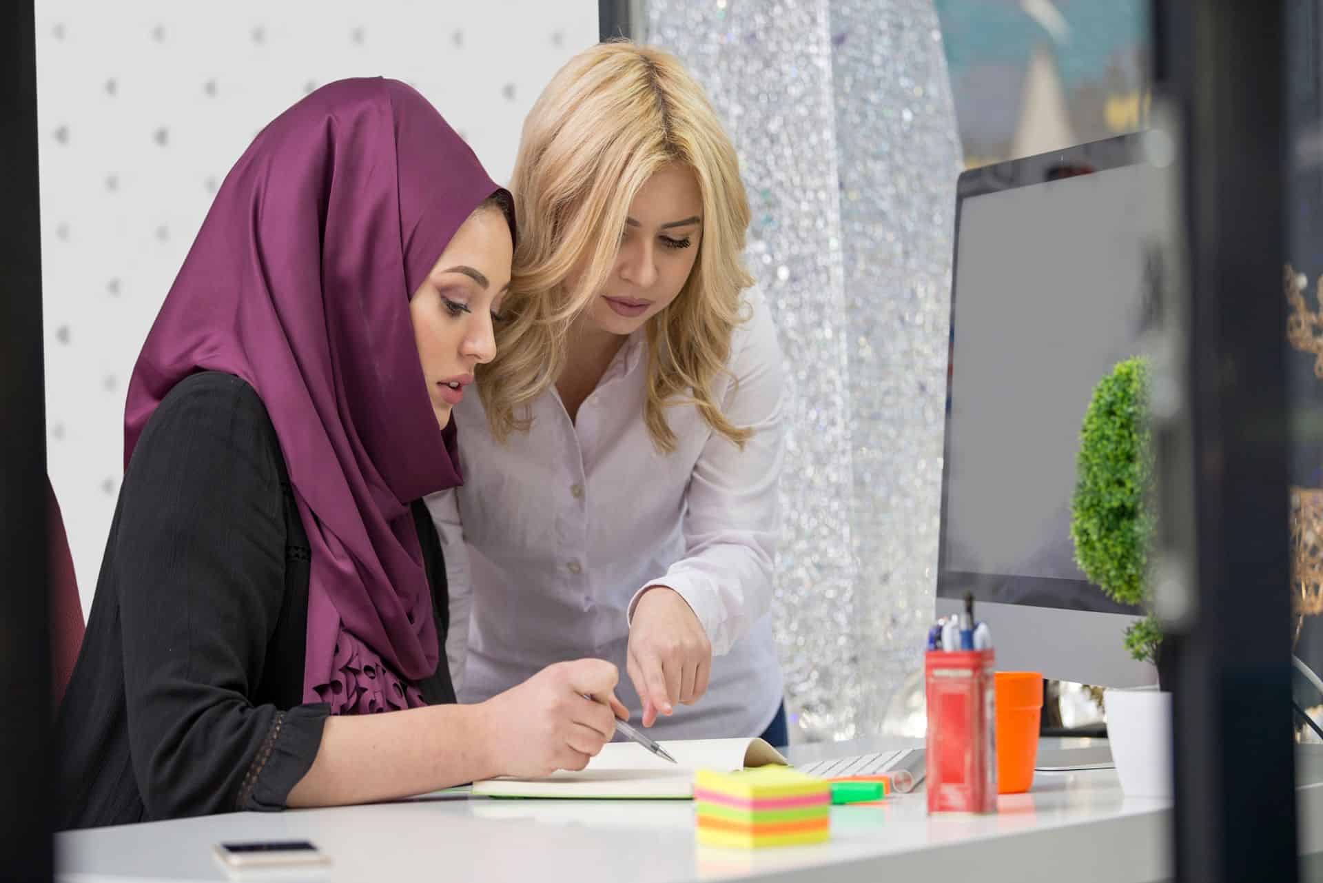 European woman helps asian muslim woman learn English