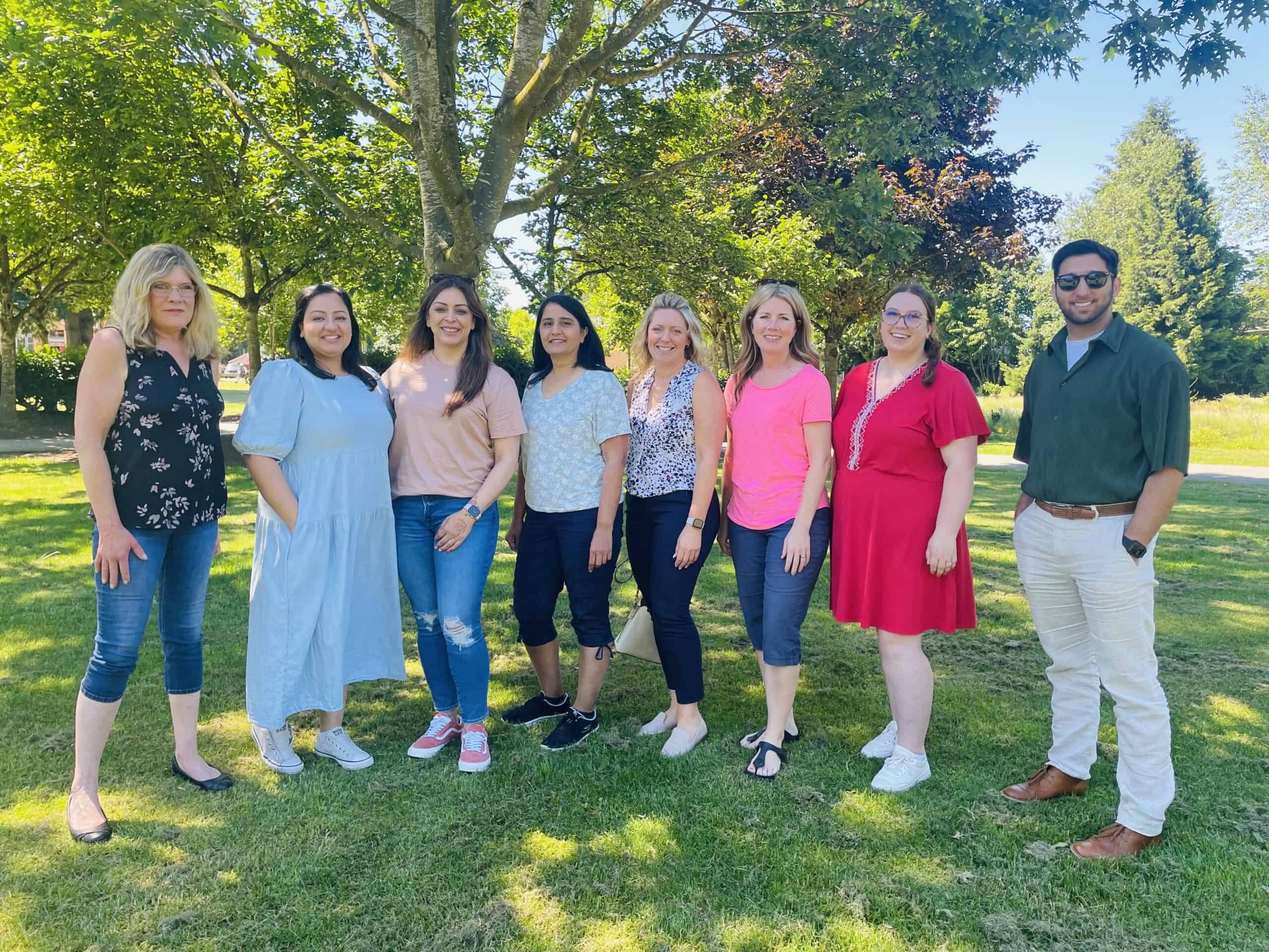 The Specialized Victim Assistance team 7 women and one man, pose in front of a tree.
