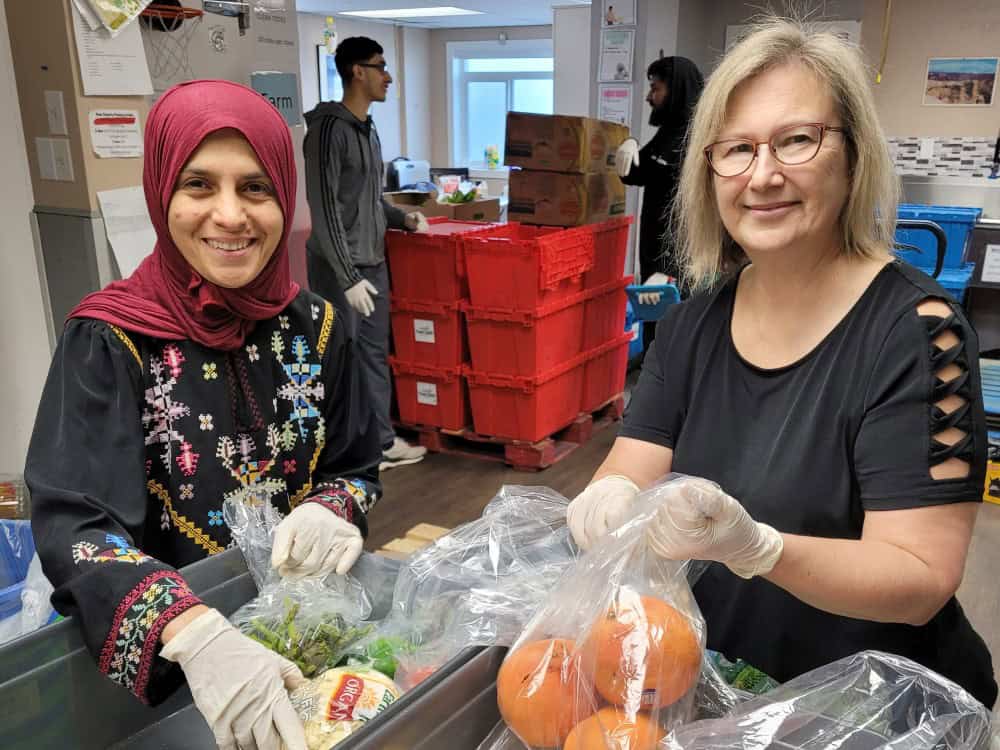 two women sort food at a food bank