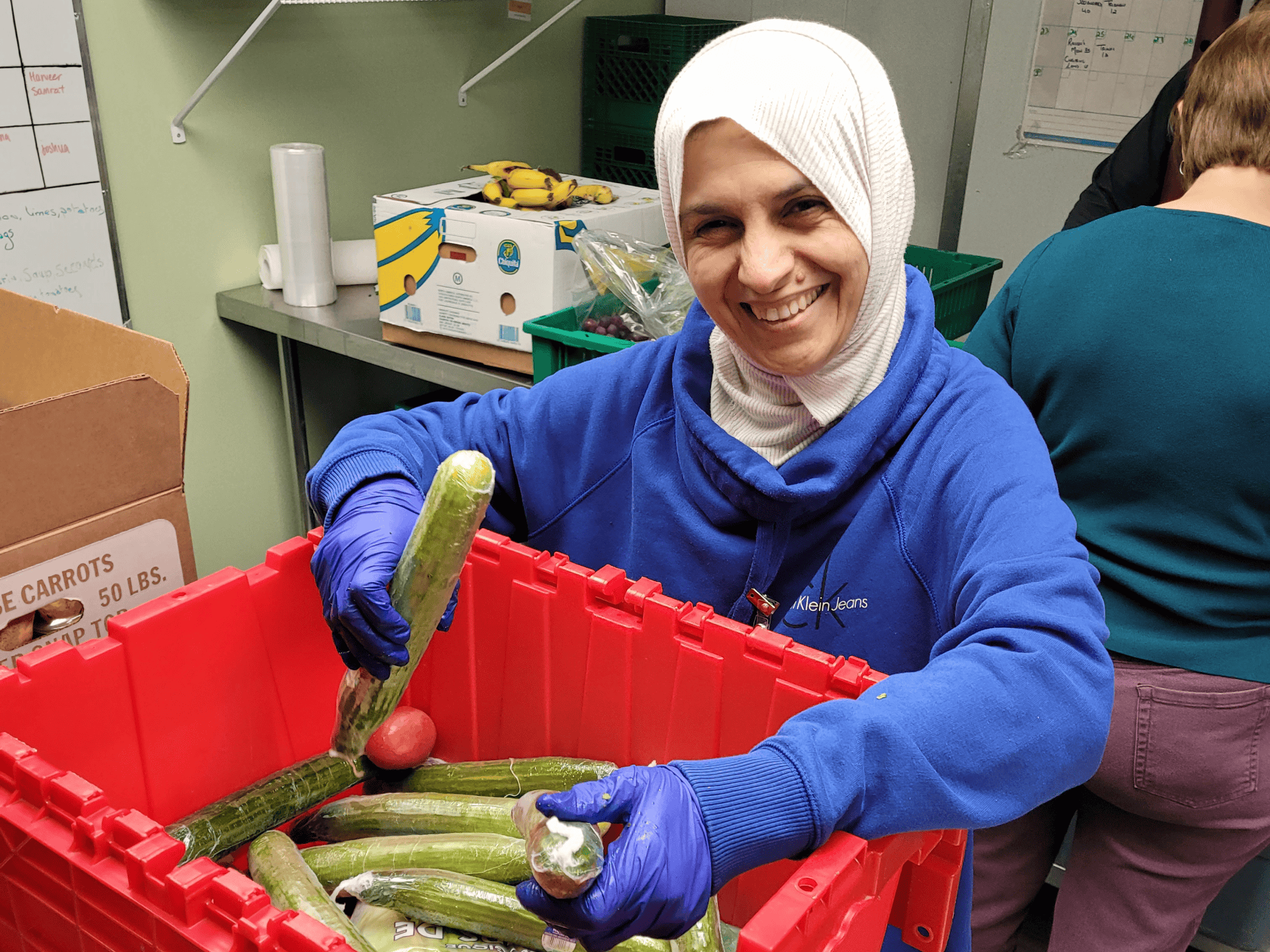 woman wearing hijab holds produce at food bank