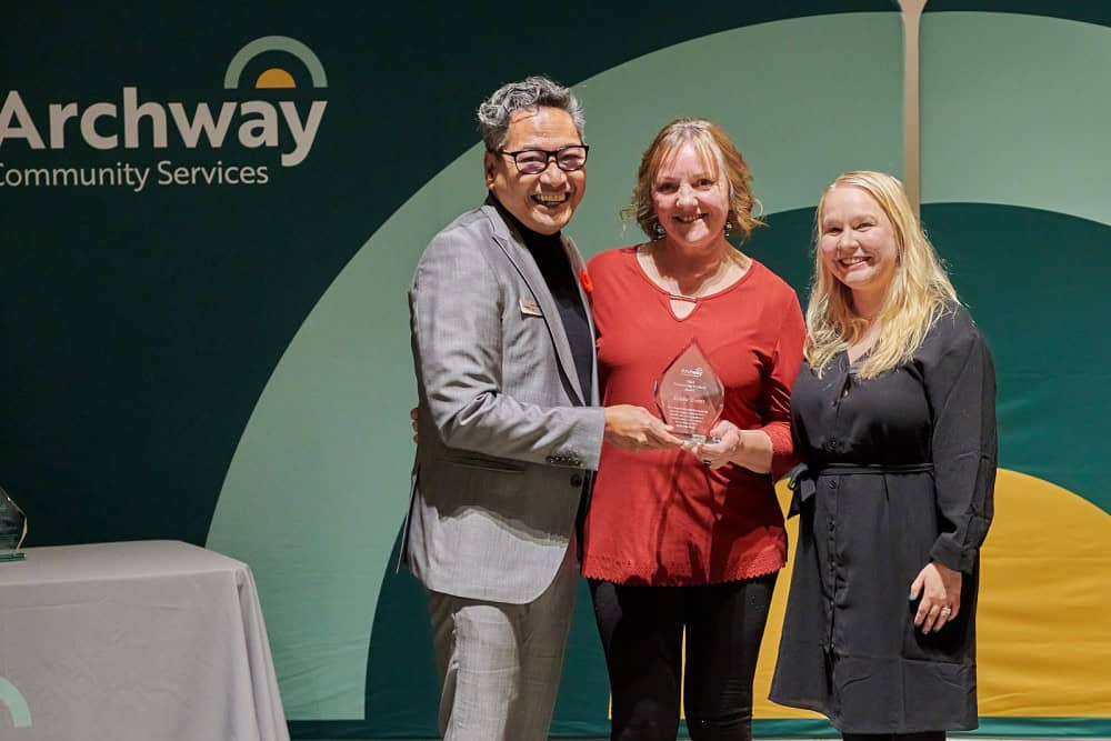 Volunteer accepts award with two Archway employees