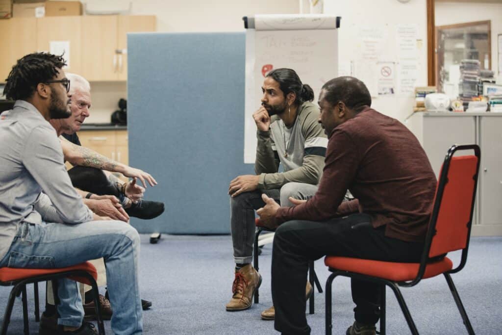 men sit in group counselling session