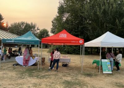 three tents at outdoor community event with sun setting in background