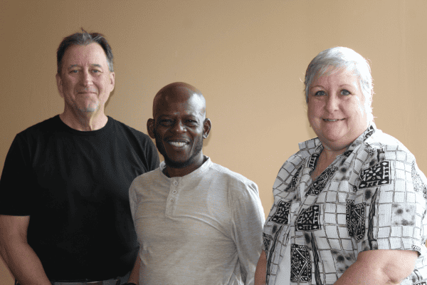 Three staff members stand together looking at camera