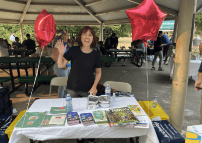 woman waves standing behind event table