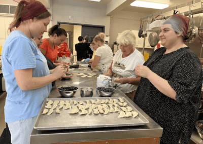Group of volunteer cooks prepare sweet perogies in industrial kitchen