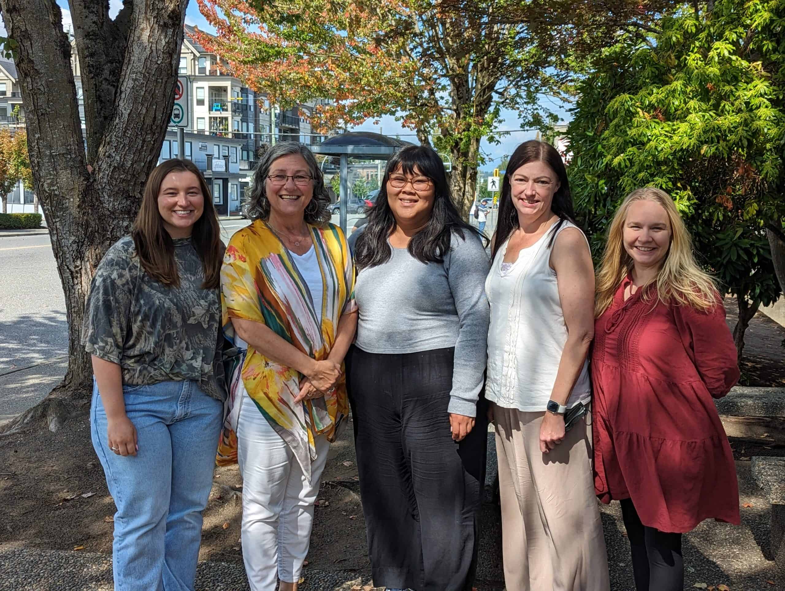 five women stand next to each other and smile at camera