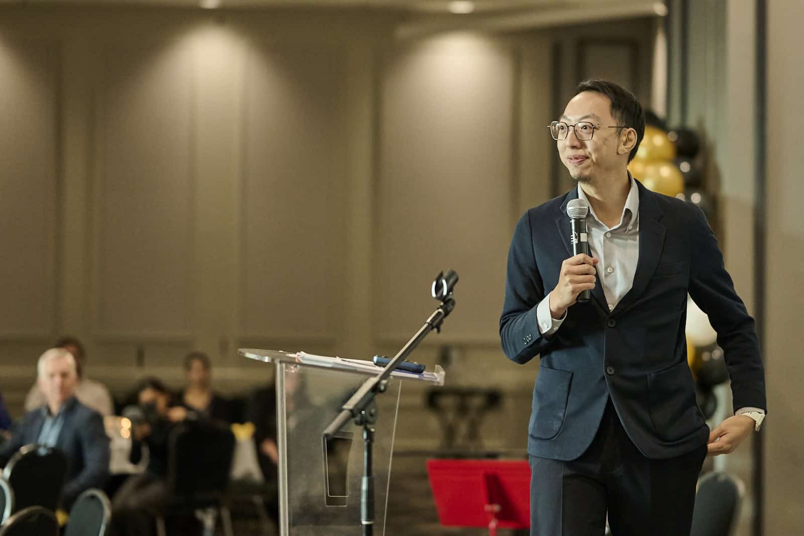Man on stage speaking to group of people