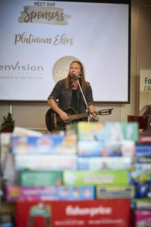 Man performs on stage behind a pile of toys