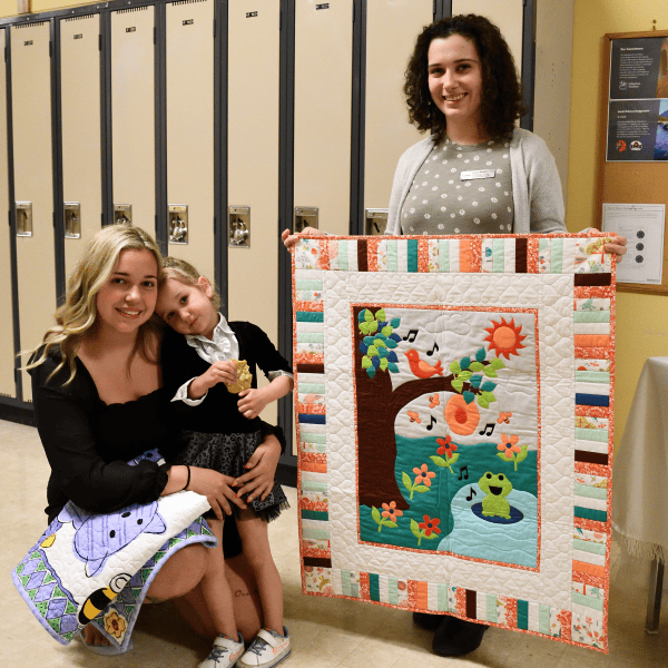 Graduate of the New Beginnings Young Parent Program with her child and staff