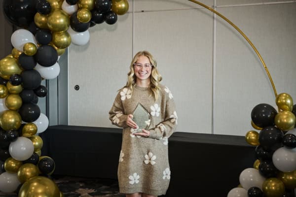 three women smile at camera in front of brick store front.