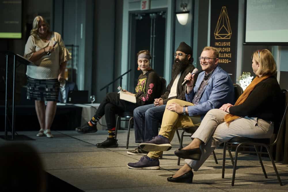 Man on stage speaking to group of people