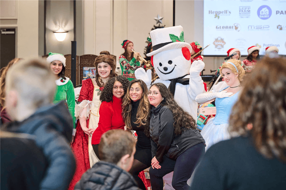 group of attendees pose with princesses and frosty mascot