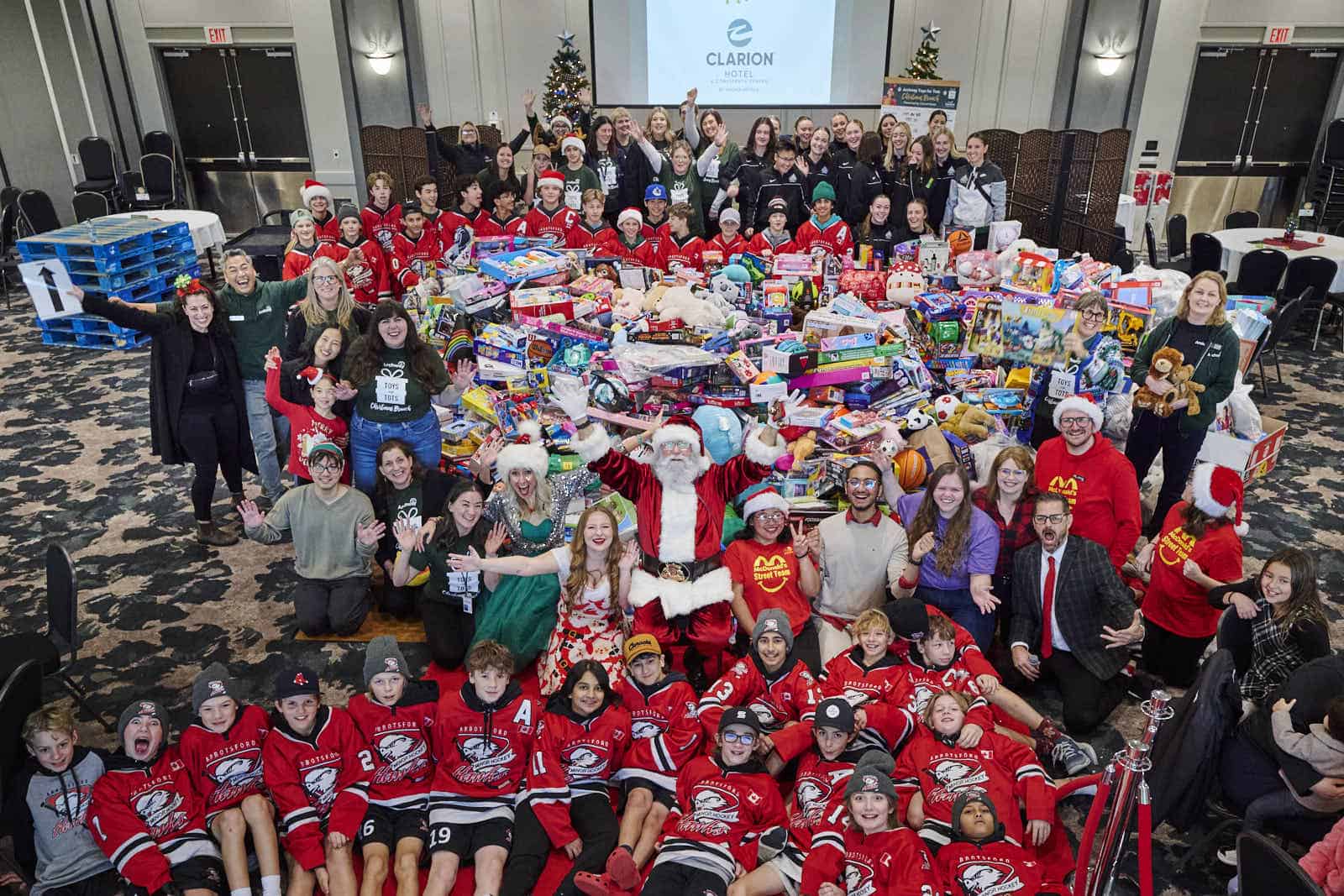 Toys for Tots 2024 toy pile with volunteers and staff standing around toys