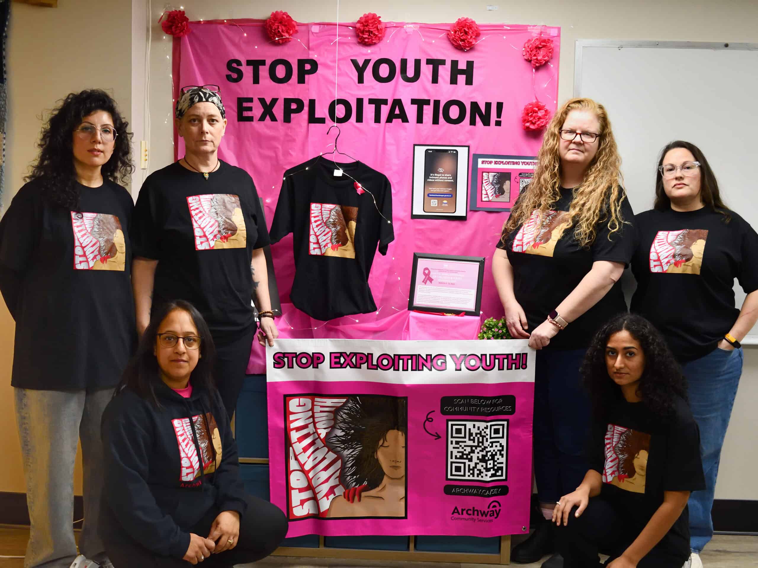 ACAT poses next to a Stop Exploiting Youth display