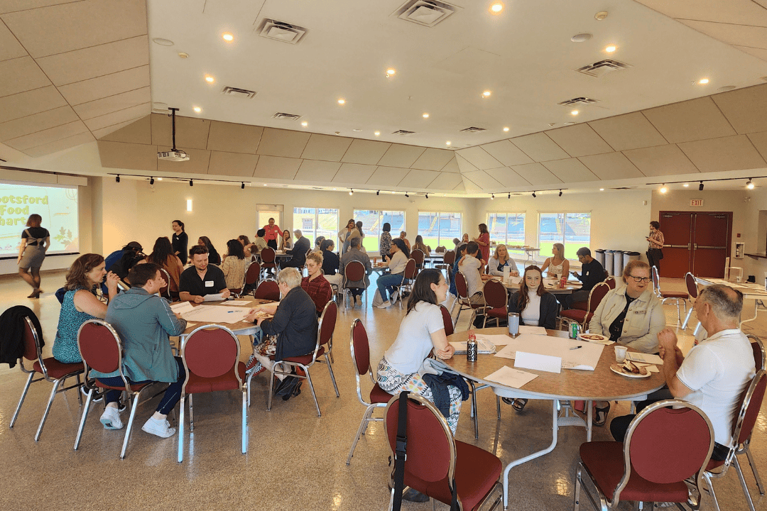 large room full of people discussing at round tables