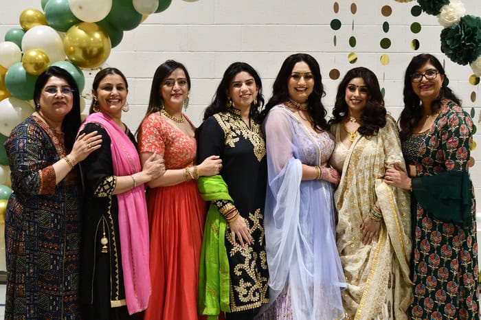 7 women wearing traditional Indian clothing posing for a picture