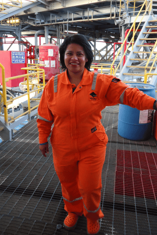Woman in orange jumpsuit works on oil rig