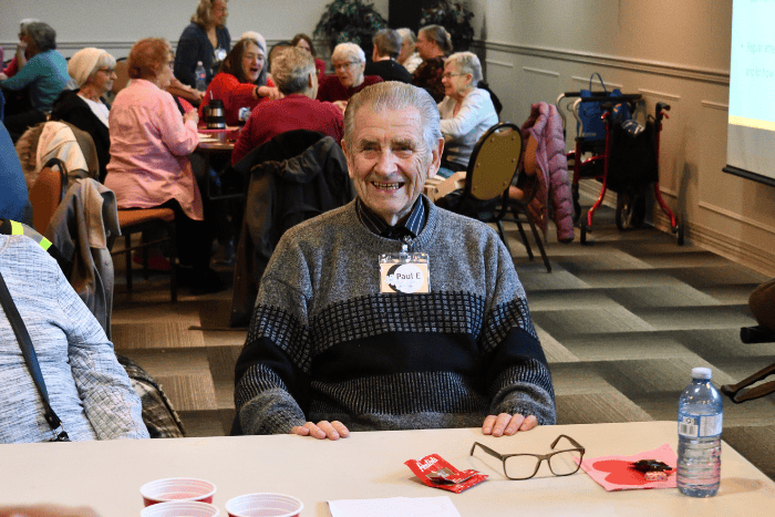 A teenager smiling, sitting across the table from another young individual 