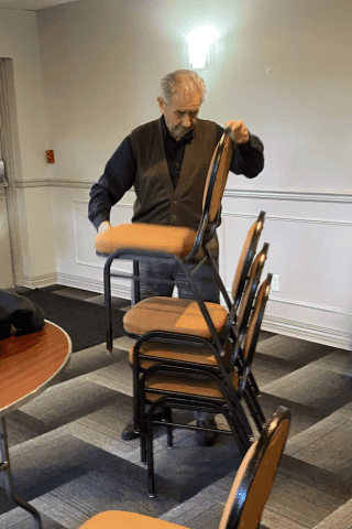 Older adult senior man stacks chairs