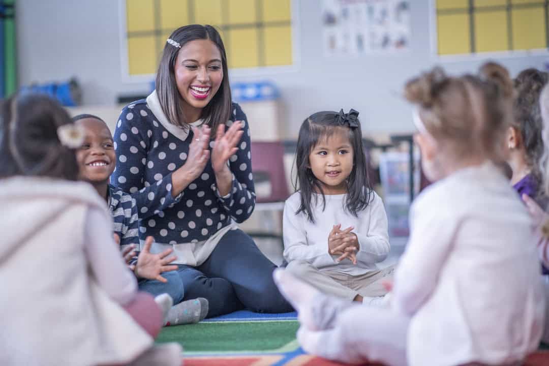 A woman clapping with children.