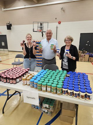 Three people holding cans of food posing for a picture