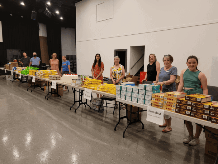 A group of volunteers standing behind tables of food