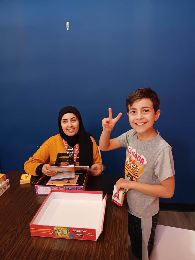 Two children sitting at a table with board games.