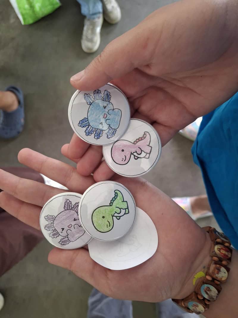 A person holding four buttons with different animals on them.
