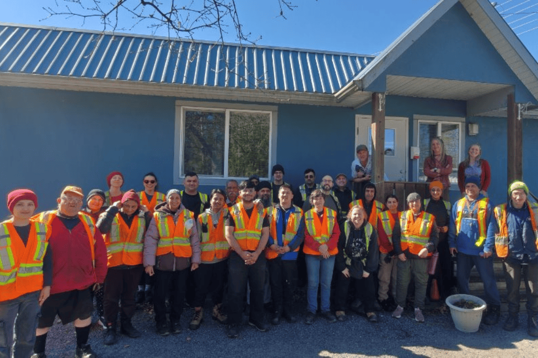Recycling Program team members standing in two rows outside blue building