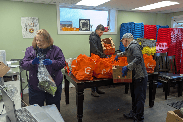 Volunteers assembling orange food hampers