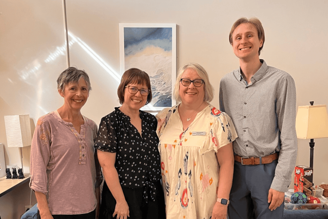 Three women and a man posing for a picture
