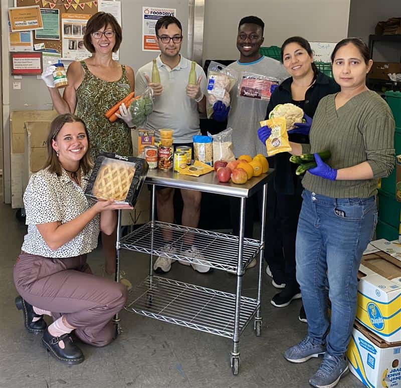 Food bank staff with Thanksgiving hamper items A group of people posing for a picture holding Thanksgiving dinner items