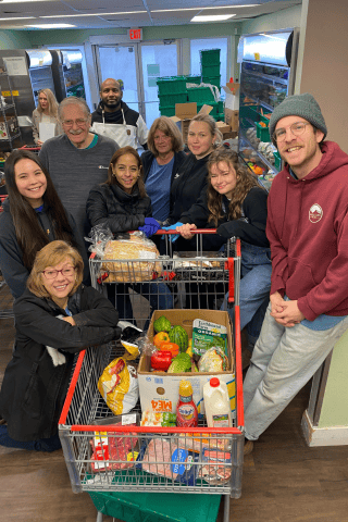 Food bank staff and volunteers Group of people around a cart full of food
