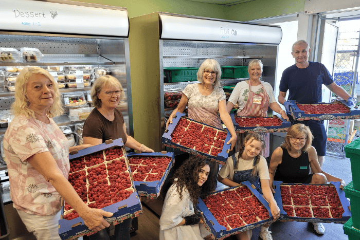 Food bank staff with a donation of raspberries A group of people holding boxes of raspberries