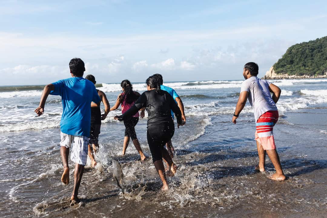 Group of people running into the ocean.