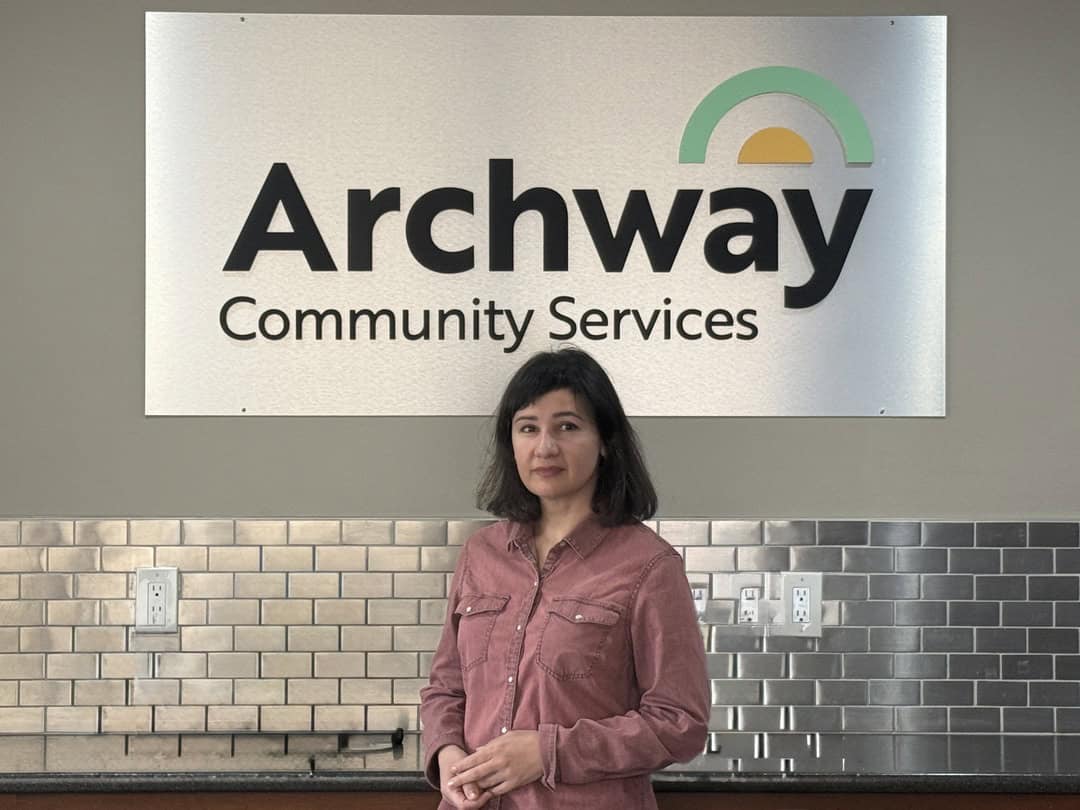 Olena standing in front of Archway Community Services logo