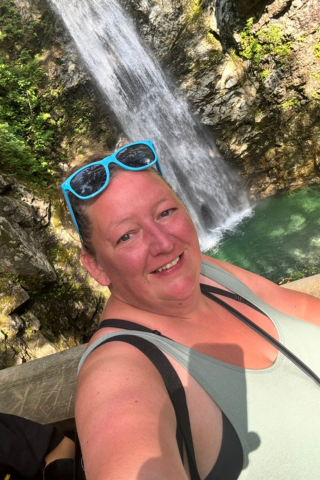 Laura stands before a waterfall, smiling.