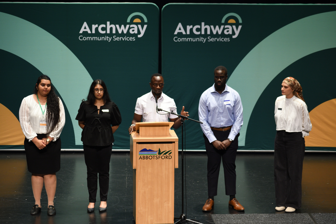 Group of 5 diverse individuals standing on stage